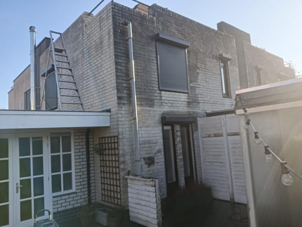 Hoe Herken je een Professionele en Ervaren Dakdekker: Red Flags en Must-Haves 5 Moderne woning met een metalen trap, zonneschermen en een stenen gevel, geschikt voor architectuur en vastgoedpresentaties.