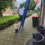 Dakrenovatie man op ladder met kind op een dak