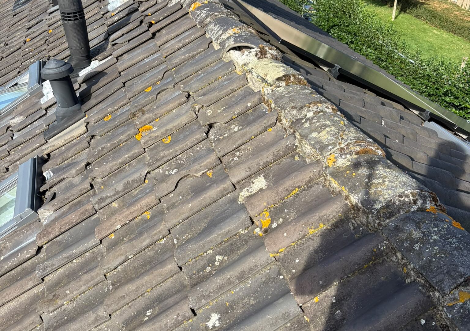 Losse nokvorsten en broos cement op het pannendak voor renovatie