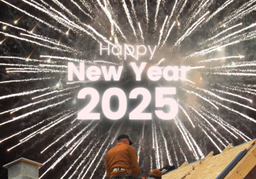 Vuurwerk met de tekst 'Happy New Year 2025' op de achtergrond, met een persoon op een dak in de voorgrond.
